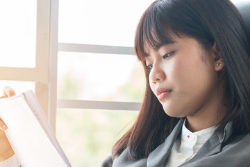 Portrait of Asian female student thinking over working homework and schedule for her exam test school in future, sitting alone by window in home, slow motion and candid shot