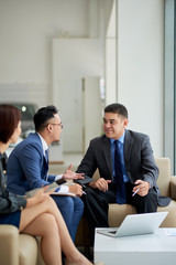Middle-aged potential customer sitting on cozy armchair and taking to highly professional...