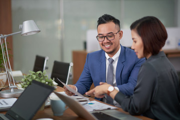 Highly professional managers gathered together at open plan office and brainstorming on start-up project, handsome man with wide smile holding document in hand