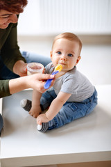 Mom gives porridge to her little child