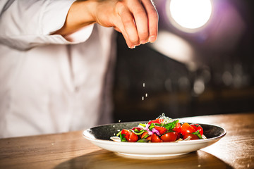 Closeup mid section of a chef putting salt in the kitchen