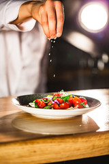 Closeup mid section of a chef putting salt in the kitchen