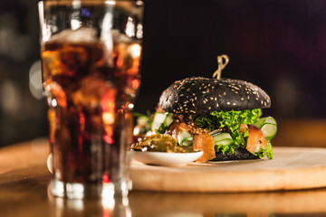 Fototapeta na wymiar A delicious fresh black hamburger with Coca Cola on a bar counter