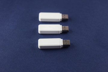 Three white flash drives on a blue background, close-up