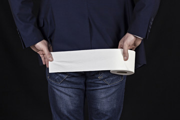 Male businessman holding a piece of toilet paper, black background