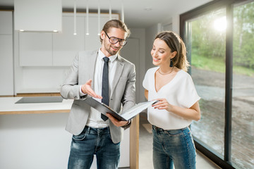 Happy woman customer standing with realtor looking on the contract of purchase or rent of an...