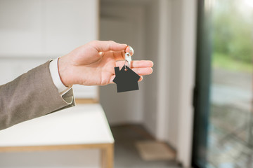 Man holding keys with house keychain in the new home intreior