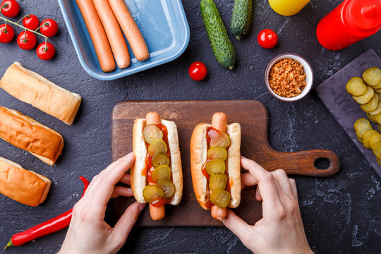 Photo from above of man doing hotdogs on cutting board on table with sausages
