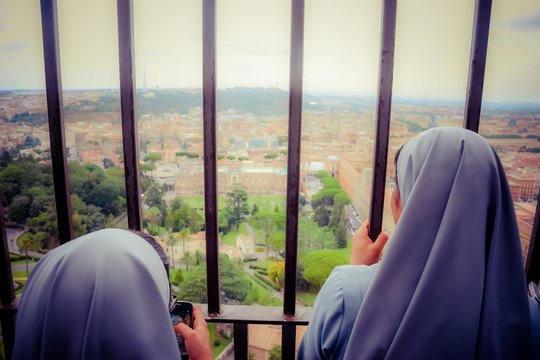 Dos monjas toman fotos con su smartphone y observan la inmensidad de Roma desde la c&uacute;pula de la Bas&iacute;lica de San Pedro (Vaticano)
