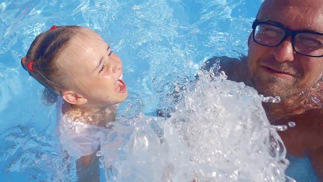 500 frames a second. happy father resting and playing with his little daughter in the pool. happy carefree childhood