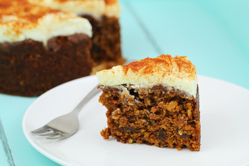 Slice of delicious carrot cake with walnuts on white plate
