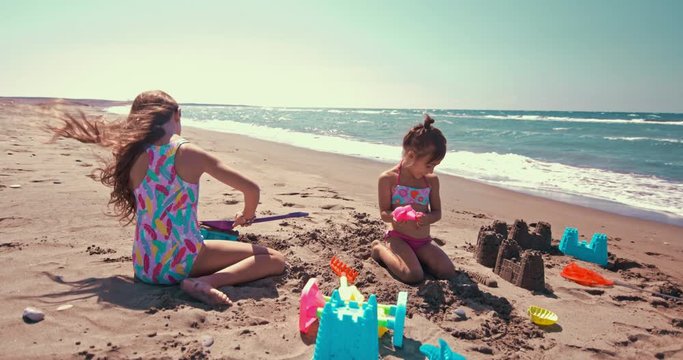 Litle girls building sandcastles on the beach on summer holidays