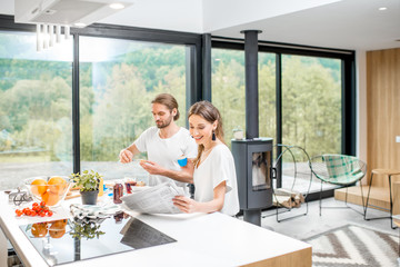 Fototapeta na wymiar Young couple having fun during a breakfast time sitting at the kitchen of the modern house interior