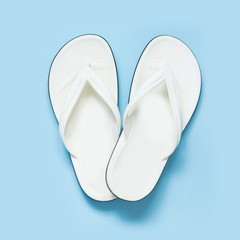 Summer concept. White flip flops over blue background. Top view.