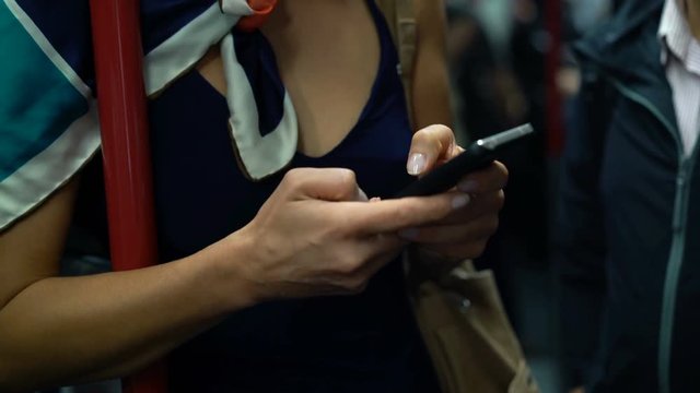 Woman hands texting on smartphone on metro train
