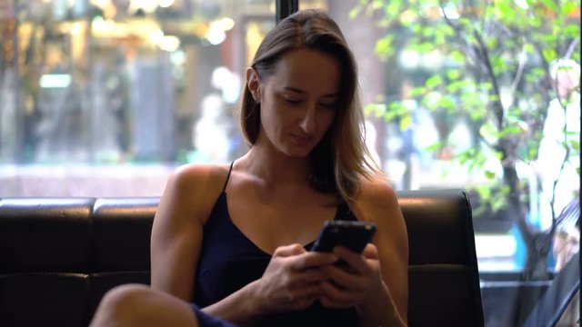 Young woman texting, surfing web on smartphone sitting in cafe 
