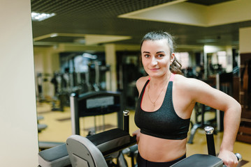 Fototapeta premium Portrait of sexy muscular girl wearing sportswear doing exercises on horizontal bar, exercises on the press in the gym club. Sport concept.