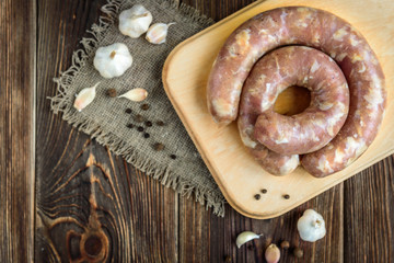 Raw chicken sausage and garlikon wooden background