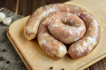 Raw chicken sausage and garlikon wooden background