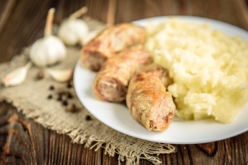 Grilled chicken sausage with mashed potato, cucumber and boiled eggs on wooden background. Healthy lunch or dinner.