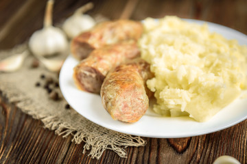 Grilled chicken sausage with mashed potato, cucumber and boiled eggs on wooden background. Healthy lunch or dinner.