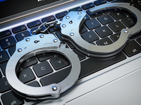 Handcuffs on the laptop keyboard. Internet cyber crime, hacking and online piracy concept.