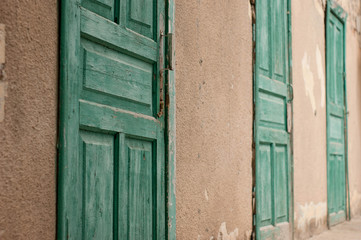 Three green wooden doors on brown concrete wall