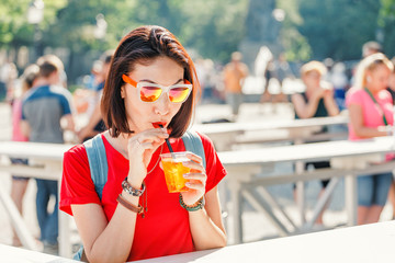 Young woman tourist drinking Aperol Spritz at the city street
