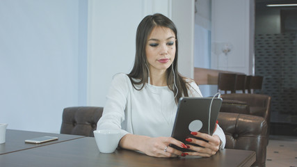 Attractive woman in earphones having video call via digital tablet