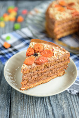 Homemade air-nut cake with chocolate cream, boiled condensed milk, candied fruit, nuts and dried apricot on grey wooden background.
