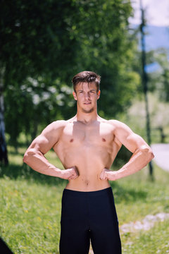 Young nude male fitness model posing outdoor