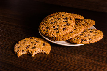 Plate with chocolate chip cookies on a dark wooden table