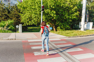 A woman violates the traffic rules and runs across the street by a red traffic light