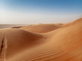 Fototapeta na wymiar The dunes of the Wahiba Sands desert in Oman at sunset during a typical summer sand storm - 1