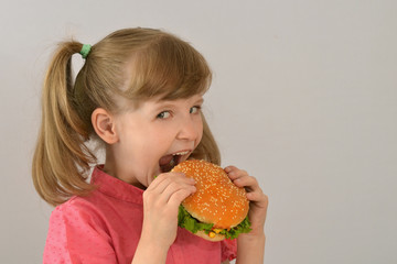 Little girl eating a sandwich. Hamburger, fast food