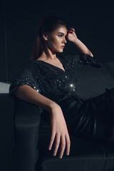Young elegant girl in black shiny suit in sequins