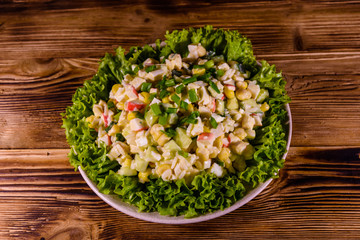 Ceramic plate with salad from crab sticks on wooden table