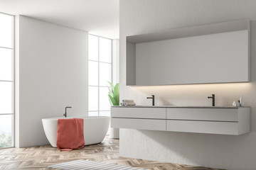 White tub in a white bathroom, armchair, sink side