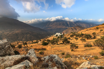 Ausblick über Kreta mit Olivenbäumen vertrocknetem Gras und weißem Dorf und Bergen mit blauem...