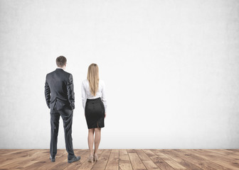 Businessman businesswoman looking at a blank wall