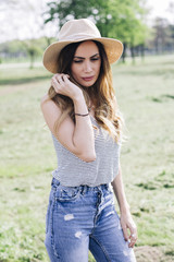 Portrait of a beautiful elegant woman with hat posing in the park