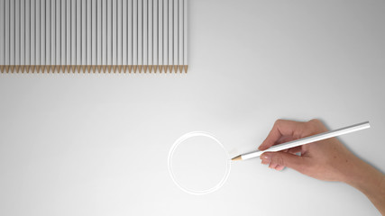 Hand holding pencil, drawing round sketch, Enso, white bright pencils on blank paper background for copy space, minimal creative design concept