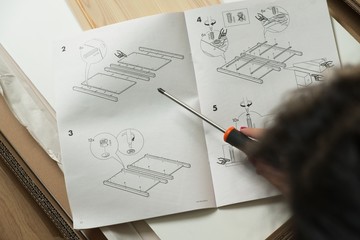 Mujer leyendo instrucciones de montaje mueble.