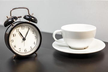 Fototapeta na wymiar alarm clock on the table and white mug, tea time, rest concept