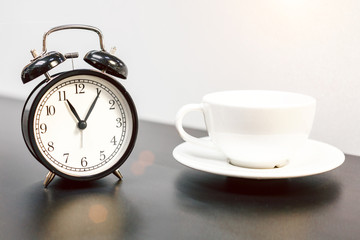 alarm clock on the table and white mug, tea time, rest concept