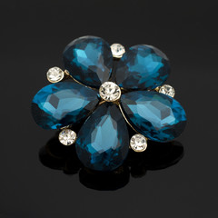 brooch flower with blue stones isolated on black