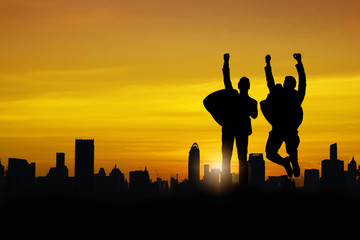 silhouette of business people team and successful teamwork group celebration and happiness jumping on top of boulding in summer sunset