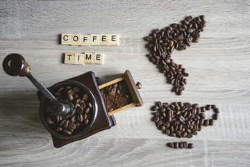 Obrazy na Szkle  coffee time quote word with Roasted coffee beans placed in the shape of a cup and saucer on wooden background, with vintage wooden grinder