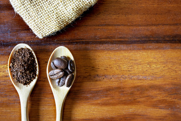 Fototapeta na wymiar Top view of wooden spoons with coffee beans, and coffee ground on wooden table