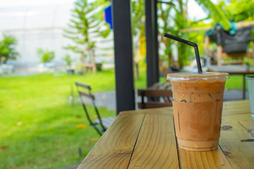 Iced coffee on a wooden table in the garden.